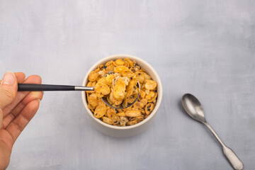 bowl of corn flakes cereals and spoon isolated on grey background.