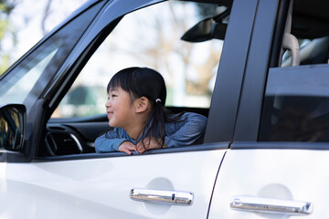 自動車の窓から外を眺める日本人の女の子