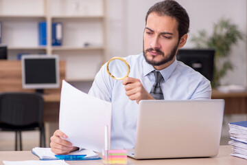 Young businessman employee holding loupe in auditing concept