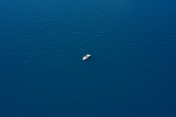 Lonely boat mooring on the water. Drone view of a boat. Aerial view of a yacht on blue water. Top view of a white boat in the blue sea. luxury motor boat.