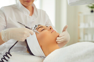 Hands of woman cosmetologist making apparatus procedure of facial oxygen therapy for young woman