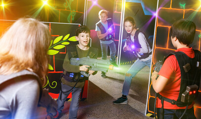 Group of happy glad teenagers with laser guns having fun on dark lasertag arena