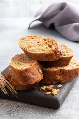 Sliced rye baguette on a gray background with cereals. Whole grain bread, a healthy food concept. Copy space.