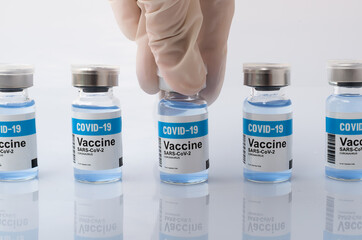 Hand wear glove picked up the COVID-19 vaccine bottle from the group