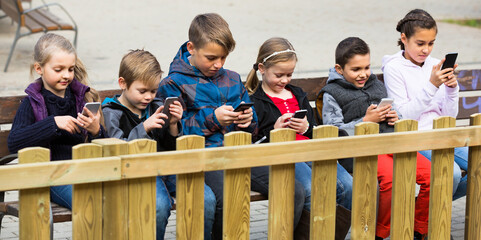 Group of juniors posing at urban street with mobile devices