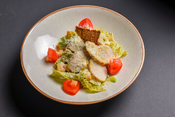 Caesar Salad served in a white plate over black background. One plate of salad for healthy and full dinner.