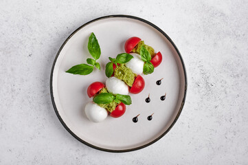 Delicious italian caprese salad with ripe tomatoes, fresh garden basil and mozzarella cheese. Top view, food style, copy space 