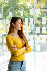 Portrait A young Asian woman making decisions while at the office window.