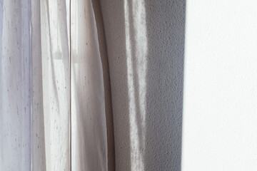 closeup of curtain with shadow on white wall