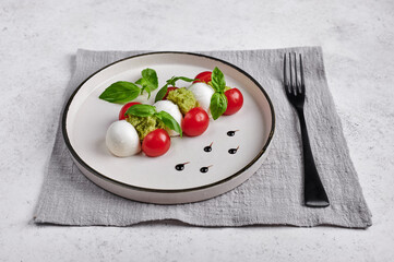 Delicious italian caprese salad with ripe tomatoes, fresh garden basil and mozzarella cheese with fork on linen napkin. Close up, food style, copy space 
