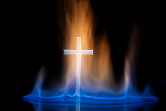 Cross or crucifix surrounded by burning fire flames.
