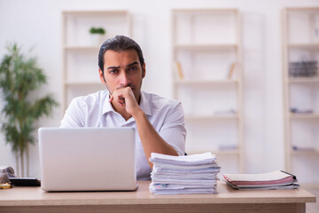 Young businessman employee unhappy with excessive work in the office