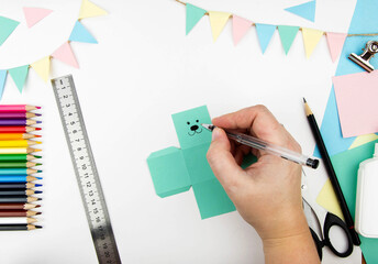 Step-by-step instructions for making a bunny box from colored paper. Step 4 - draw a bunny face.