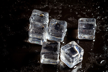 ice cubes reflection on black table background.