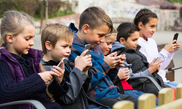 Group of children playing at urban street with mobile devices