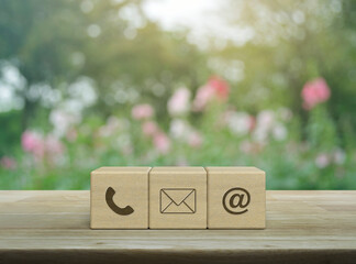 Telephone, mail, email address icon on wood block cubes on wooden table over blur pink flower and...