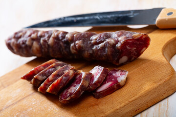 Sliced French dry sausage on wooden cutting board