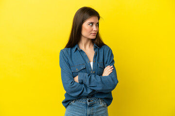 Young caucasian woman isolated on yellow background keeping the arms crossed