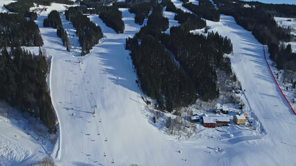Fototapeta na wymiar Aerial view of a large alpine winter ski resort with ski lifts, skiers and snow covered slopes.