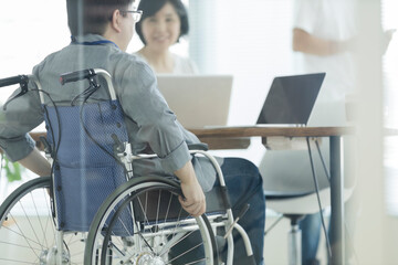 Obraz premium オフィスで働く車椅子の男性
