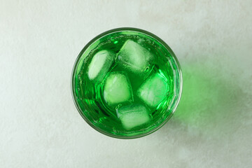 Glass of green soda on white textured background