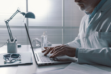 Professional doctor typing on a laptop