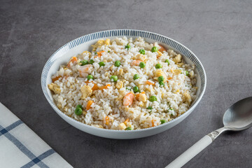 Three jewel rice. Fried rice with prawns, peas and carrots. One spoon and cloth
