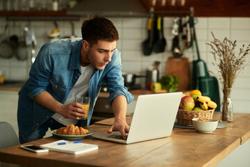 Young man surfing the net on laptop at home.