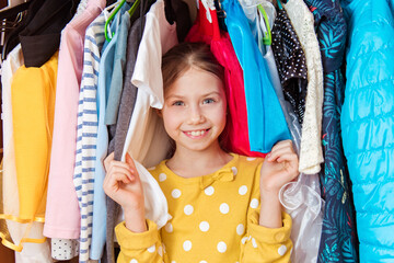 Portrait of a happy attractive teen girl making choices in wardrobe