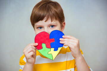 Kid boy hands holding puzzle heart, child mental health concept, world autism awareness day, teen autism spectrum disorder awareness concept