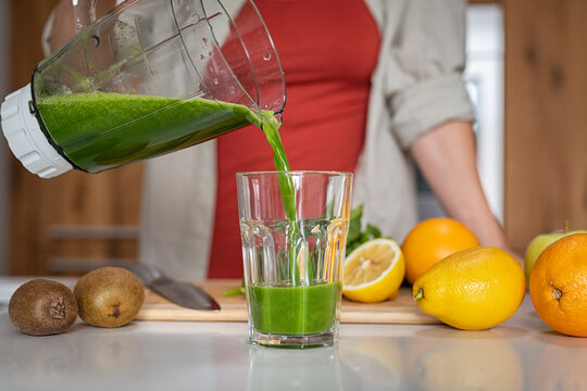 Girl pouring green handmade juice in glass