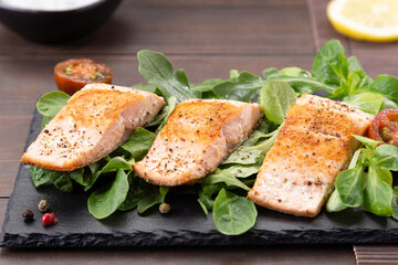 close up salmon fillets on slate dish on wooden table background.