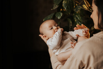 Beautiful mom supports and tenderly cuddles the newborn baby. Pretty mother looking with love and...