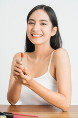 attractive beautiful mixed race asian woman applying lipstick on her lips over white background