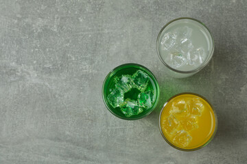 Glasses of different soda on gray background