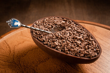 Stuffed chocolate easter egg with grated chocolate on the top with a spoon on a wooden stand on a wooden table.