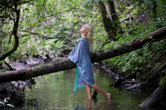 Portrait of a naked elegant girl in a green forest with a blue scarf