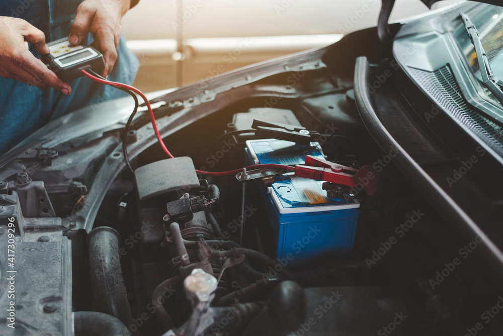 Poster selective focus an auto mechanic uses a multimeter voltmeter to check the voltage level in a car bat