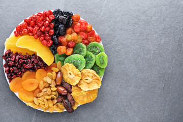 Dried fruits and berries on a plate top view. Lemons, oranges, raisins, cranberries, kiwi,...