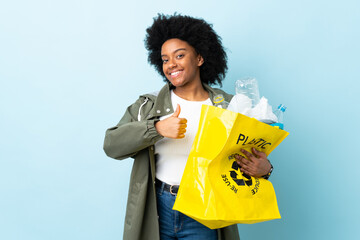 Young African American woman holding a recycle bag isolated on colorful background giving a thumbs up gesture