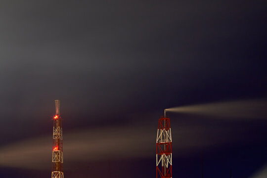 Signaled With Red Lights Smoke Pipes Of Petrochemical Plant At Night Dark Dramatic Sky Long Time Exposure Shot With Copyspace. Concept Of Environment Pollution Greenhouse Effect Global Warming