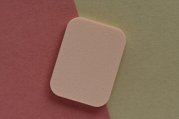 Makeup sponge isolated on pink and beige background.