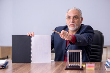 Old teacher physicist sitting in the classroom