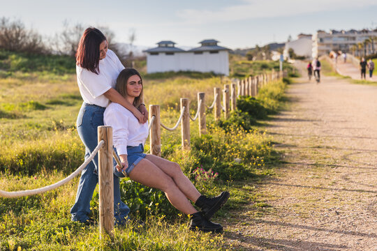 Joven pareja homosexual disfrutando de un d&iacute;a en el paseo, abraz&aacute;ndose vestidas con vaqueros y camisas blancas. 