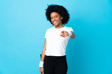 Young African American woman isolated on blue background playing tennis and pointing to the front