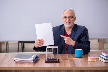 Old teacher physicist sitting in the classroom