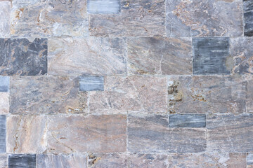 The wall of the building is faced with polished marble slabs of various colors and sizes.