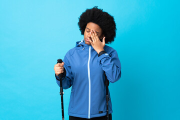 Young Africa American with backpack and trekking poles isolated on blue background with headache