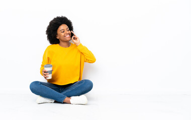 Young African American woman sitting on the floor holding coffee to take away and a mobile