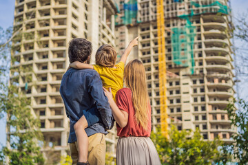 Family mother, father and son looking at their new house under construction, planning future and dreaming. Young family dreaming about a new home. Real estate concept